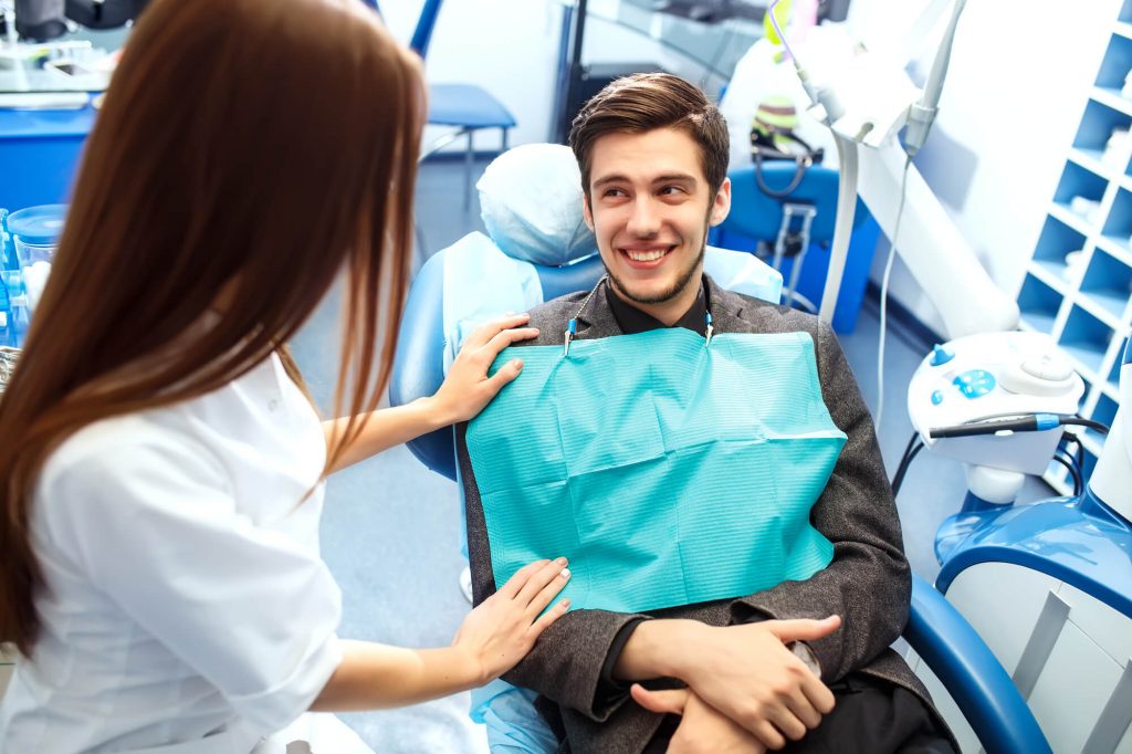 Female hygienist comforting young male patient